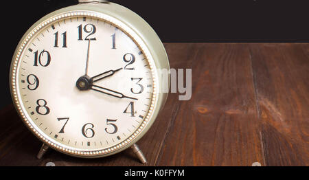 Alte antike Wanduhr auf Weiß auf Holztisch, isoliert Stockfoto