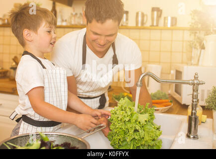 Vater mit kleinen Sohn wäscht Gemüse in der Küche vor dem Essen Stockfoto