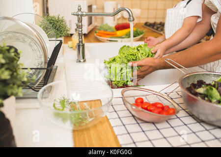 Vater mit kleinen Sohn wäscht Gemüse in der Küche vor dem Essen Stockfoto