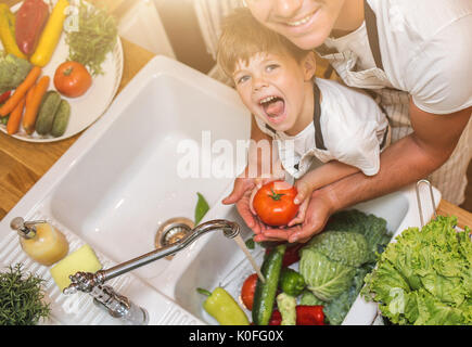 Vater mit kleinen Sohn wäscht Gemüse in der Küche vor dem Essen Stockfoto