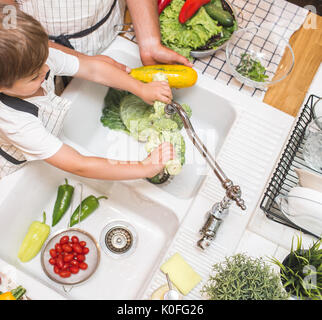 Vater mit kleinen Sohn wäscht Gemüse in der Küche vor dem Essen Stockfoto