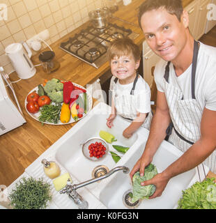 Vater mit kleinen Sohn wäscht Gemüse in der Küche vor dem Essen Stockfoto