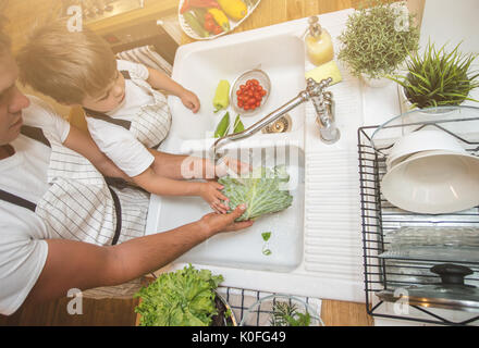 Vater mit kleinen Sohn wäscht Gemüse in der Küche vor dem Essen Stockfoto