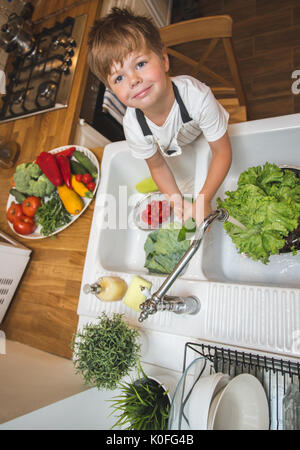 Little Boy wäscht Gemüse in der Küche vor dem Essen Stockfoto