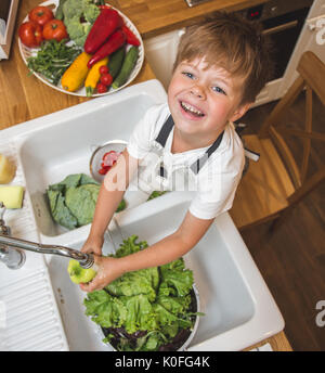 Little Boy wäscht Gemüse in der Küche vor dem Essen Stockfoto