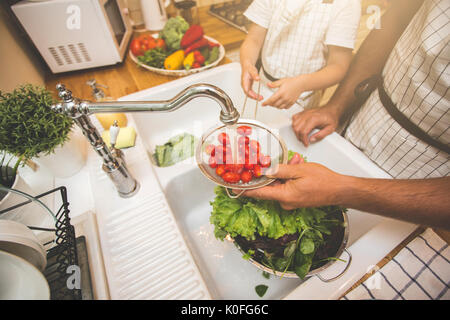 Vater mit kleinen Sohn wäscht Gemüse in der Küche vor dem Essen Stockfoto