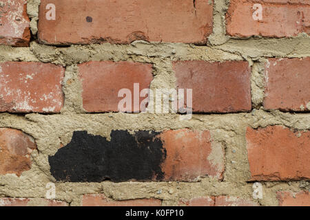 Der Hintergrund ist aus roten Ziegeln mit einem welligen Relief, Risse