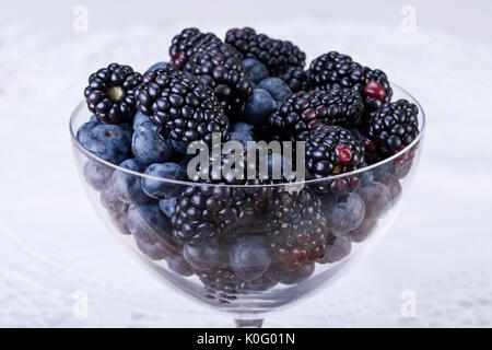 Stapel von Heidelbeeren und Brombeeren in einem Kristall Glas Schüssel Stockfoto