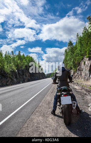 Motorrad Fahrer bereit ist, fahren auf der Asphaltstrasse zu starten, auf dem Motorrad sitzen, Rückansicht Stockfoto