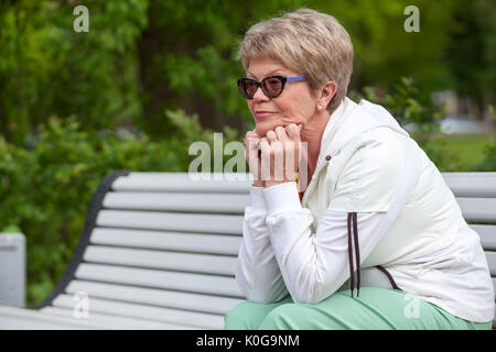 Nachdenklich senior Europäerin ruht auf der Bank, wegsehen, Exemplar Stockfoto