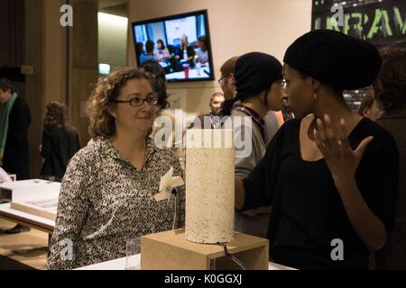 Ein Student und eine ältere Frau stand vor einem Kunstwerk auf einem hohen Tabelle angezeigt, der Student beschreibt die Arbeit der Frau im Entwirren der Code Öffnung an der Johns Hopkins Universität Sheridan Bibliotheken, 2016. Mit freundlicher Genehmigung von Eric Chen. Stockfoto