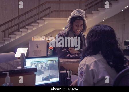 Ein Student lächelt, als er mit einem Sicherheitsbeamten spricht, der 2014 in der Milton S. Eisenhower Library auf dem Homewood Campus der Johns Hopkins University in Baltimore, Maryland, arbeitet. Mit Freundlicher Genehmigung Von Eric Chen. Stockfoto