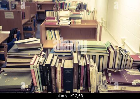 Ein Doktorand sitzt in seinem Arbeitsraum, umgeben von Bücherstapeln, in der Milton S. Eisenhower Library auf dem Homewood Campus der Johns Hopkins University in Baltimore, Maryland, 2015. Mit Freundlicher Genehmigung Von Eric Chen. Stockfoto