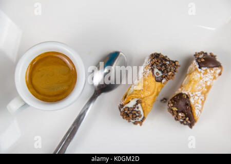 Sizilianische Cannoli und Kaffee auf weißem Teller auf hölzernen Tisch Stockfoto