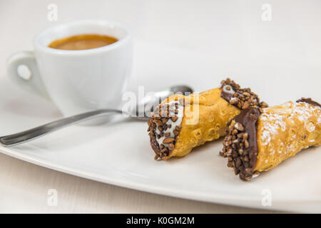 Sizilianische Cannoli und Kaffee auf weißem Teller auf hölzernen Tisch Stockfoto