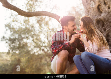 Liebespaar unter einem großen Baum im Park im Herbst Stockfoto