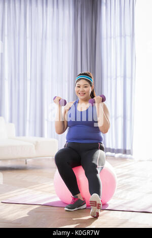 Junge lächelnde fette Frau Training mit Kurzhanteln Stockfoto