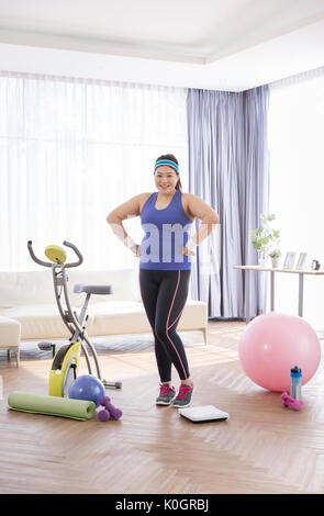 Junge lächelnde fette Frau, die mit der Ausübung Ausrüstungen posing Stockfoto
