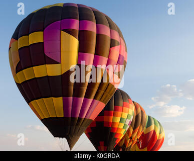 Vier bunte aufgeblasenen Ballons in einer Reihe. Licht blauer Himmel mit cumulus Wolken im Hintergrund. Stockfoto