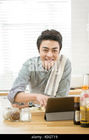 Portrait von lächelnden einzelner Mann Kochen mit Tablet Stockfoto