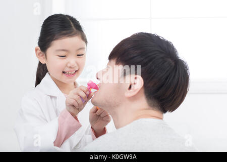 Lächelnde Mädchen und ihr Vater spielen Krankenhaus Stockfoto