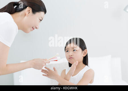 Lächelnde Mutter erzählt ihrer Tochter Zähne putzen Stockfoto