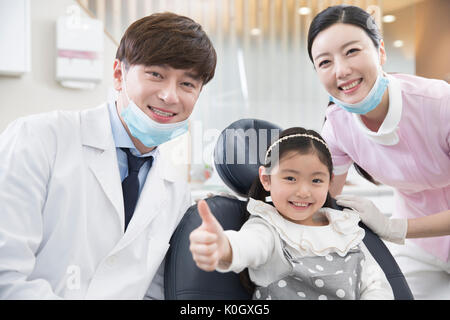 Lächelnd Zahnarzt, Mädchen, Patienten und Zahnarzthelfer Stockfoto