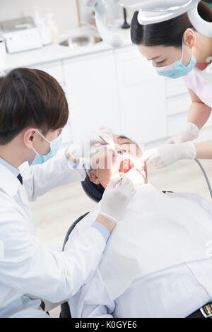 Hohe Betrachtungswinkel von Zahnarzt und Dentalhygienikerin heilen Ein älterer männlicher Patient Stockfoto