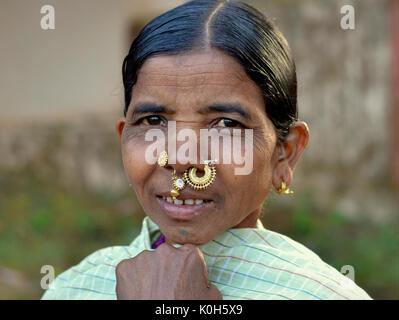 Ältere indische Adivasi-Frau mit kostbaren goldenen Nasenstollen/Ringen/Schmuck und Ohrringen aus Stammes lächelt für die Kamera. Stockfoto