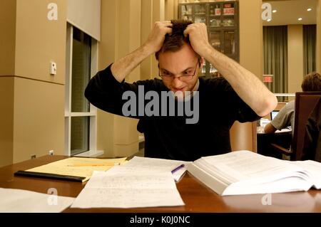 Ein nervös Student packt seine Haare wie er schaut auf seine Notizen im Lesesaal der Brody Learning Commons, eine Studie Raum und Bibliothek auf dem Homewood Campus der Johns Hopkins University in Baltimore, Maryland, 2015. Mit freundlicher Genehmigung von Eric Chen. Stockfoto