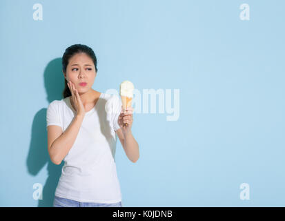 Schönheit süße Studentin leiden empfindliche Zähne Krankheit auf Eis zu essen in der blauen Wand Hintergrund. Stockfoto