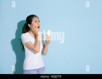 Nette junge Studentin Eis essen Gefühl Zähne schmerzhaft und gefunden in sensiblen Zahnproblems Blick auf blauem Hintergrund leere Bereich auf g möchten Stockfoto