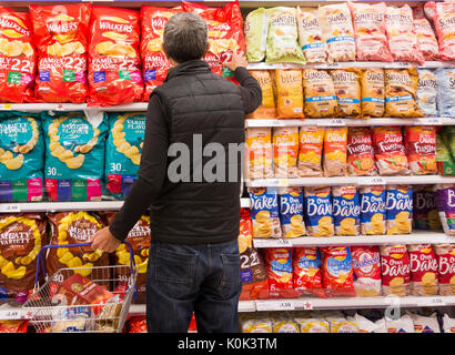 Mann kaufen Großes pack Chips in Tesco Supermarkt. Großbritannien Stockfoto