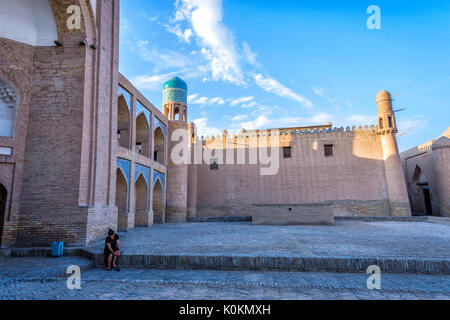 Chiwa, Usbekistan - 6. SEPTEMBER: Frau sitzt vor der alten Madrassa in Chiwa Altstadt. September 2016 Stockfoto