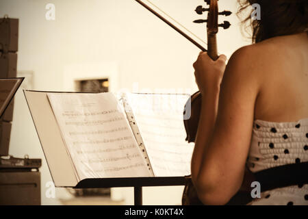 Blick auf die Noten und die Geigerin bei einem Konzert der klassischen Musik in der Luft. Stockfoto