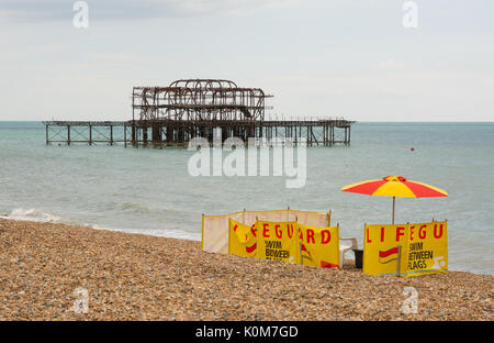 Rettungsschwimmer Post auf dem Kiesstrand an der Brighton, East Sussex, England. Mit ruiniert West Pier im Hintergrund. Stockfoto