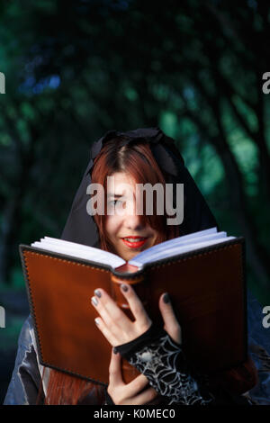 Bild der Hexe in Mantel mit Buch Stockfoto