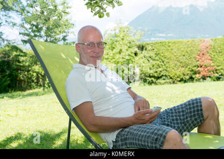 Entspannen im Liegestuhl in seinem Garten, Sommerzeit Senior woman Stockfoto