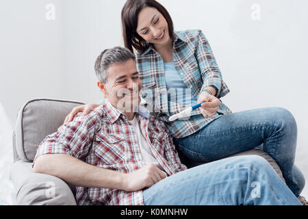 Glücklich lächelnde Paar zu Hause einen Schwangerschaftstest Stockfoto