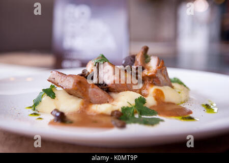 Kartoffeln und Fleisch auf einem Schild an einem Holztisch Stockfoto