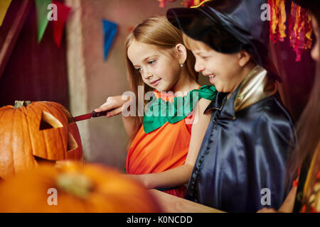 Kinder personenbezogen mit Schnitzereien einen Kürbis Stockfoto