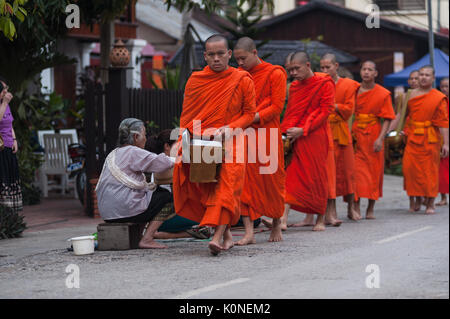 Die Laien, von Luang Prabang, Laos, engagieren sich in der täglichen Morgen Tak Bat Zeremonie, die die traditionelle Bindung zwischen Mönchen und monas veranschaulicht Stockfoto