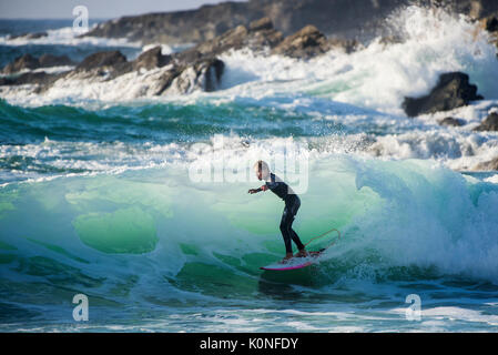 Ein junger Surfer auf einer Welle an Fistral Beach in Newquay. Stockfoto