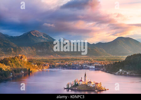 Bunte Sonnenaufgang über dem Bleder See, den umliegenden Hügeln, seine Insel und das karawanks Bergen im Hintergrund, in Slowenien. Stockfoto