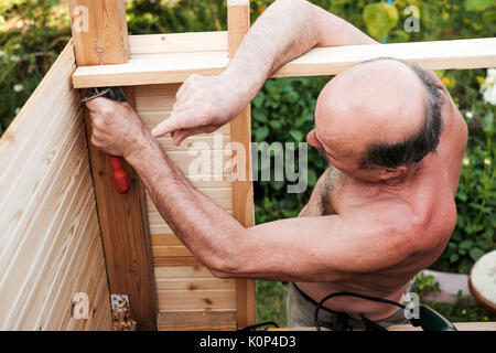 Reifer Mann mit Hilfe der Werkzeuge außerhalb der Gebäude Stockfoto