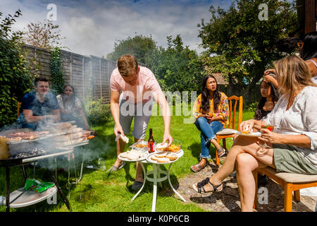 Ein junger Mann kochen Essen in einer traditionellen Familie Grill, Sussex, UK Stockfoto