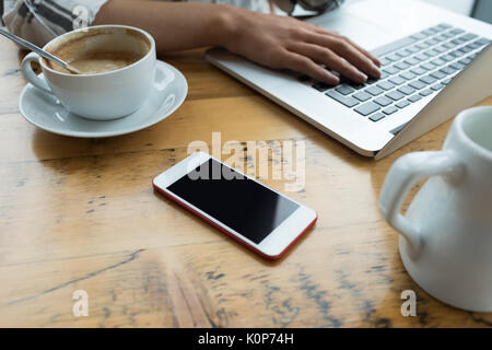 7/8 Hand der Frau mit Laptop am Tisch im Cafe Stockfoto