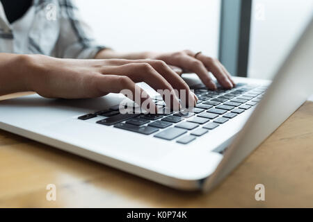 7/8 Hand der Frau mit Laptop am Tisch im Cafe Stockfoto