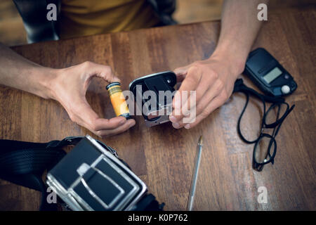 Zugeschnittenes Bild des Fotografen entfernen Haspel von der Kamera am Tisch im Studio Stockfoto