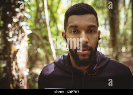 Close up Portrait des jungen Mannes, Musik hören beim Stehen in Wald Stockfoto